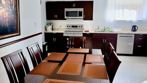 Une cuisine moderne avec des meubles de rangement en bois foncé, un four en acier inoxydable et une table à manger avec des chaises.