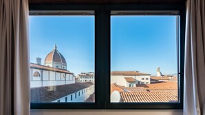 Janela com vista para um edifício histórico com cúpula e telhados em azulejos.