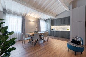 Een moderne keuken met grijze kastjes, een houten eettafel en een blauwe fauteuil.