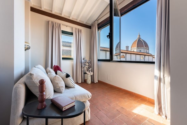 A balcony with a sofa, a small table, and a view of a dome-shaped building.