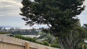 Uma cerca de madeira com vista para uma árvore e um corpo d'água ao fundo.