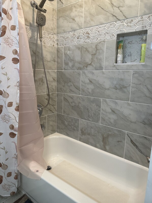 A bathroom with a bathtub, shower, and tiled walls.