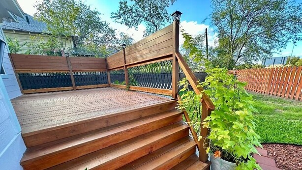 A wooden outdoor staircase leading to a deck area with a metal railing and potted plants. - A Gem off of IH-10  (San Antonio)