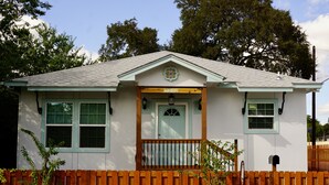 A small, single-story house with a white exterior, a wooden porch, and a mailbox. - A Gem off of IH-10  (San Antonio)