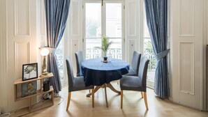 Un coin repas avec une table ronde, quatre chaises, une nappe bleue, une lampe et une plante en pot.