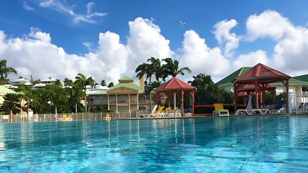 Una piscina con agua azul cristalina, rodeada de sillones de descanso y dos gazebos.