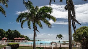 Zona de piscina con palmeras, vista al océano y un pabellón.