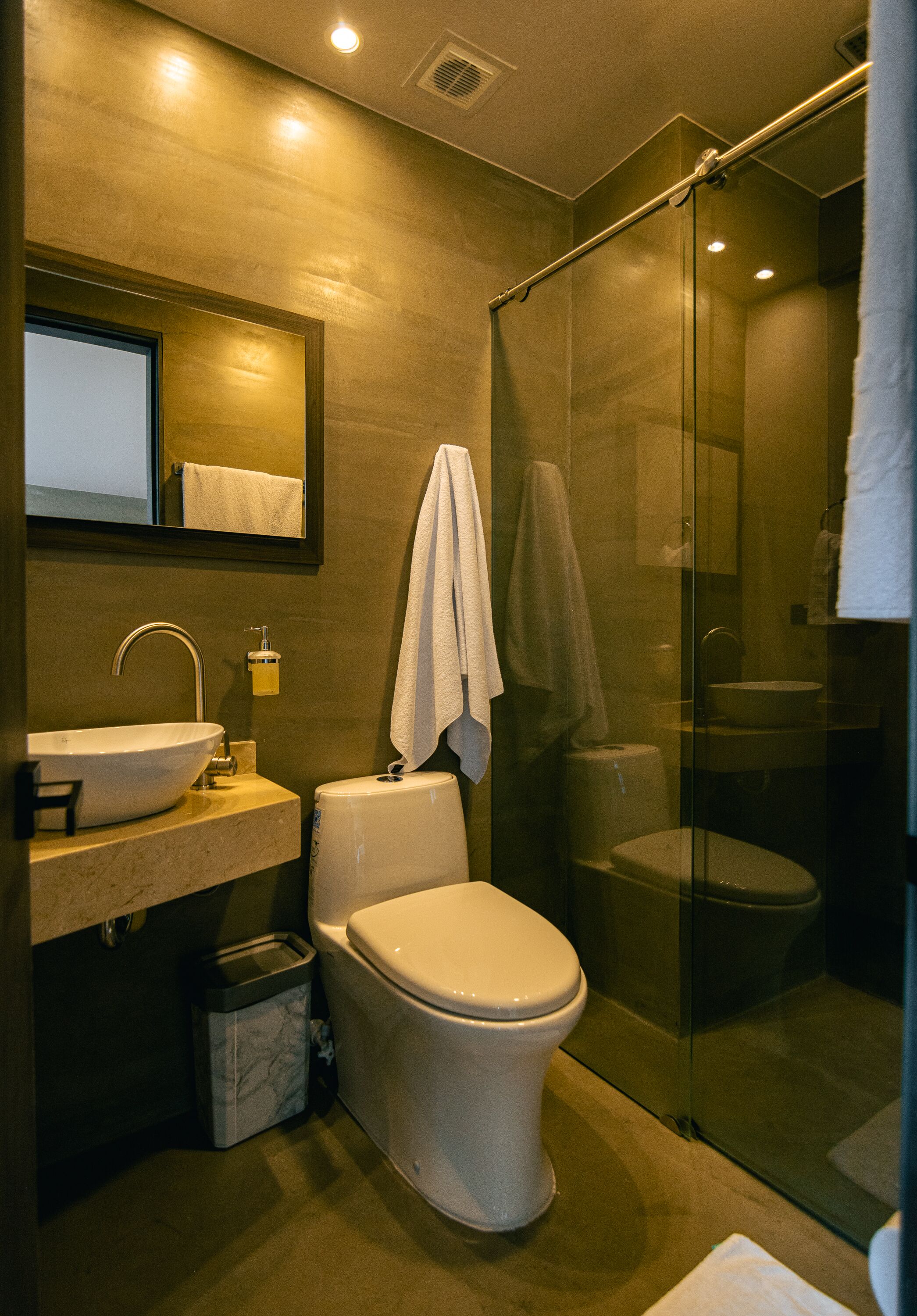A modern bathroom with a glass-enclosed shower, a white sink, and a toilet.