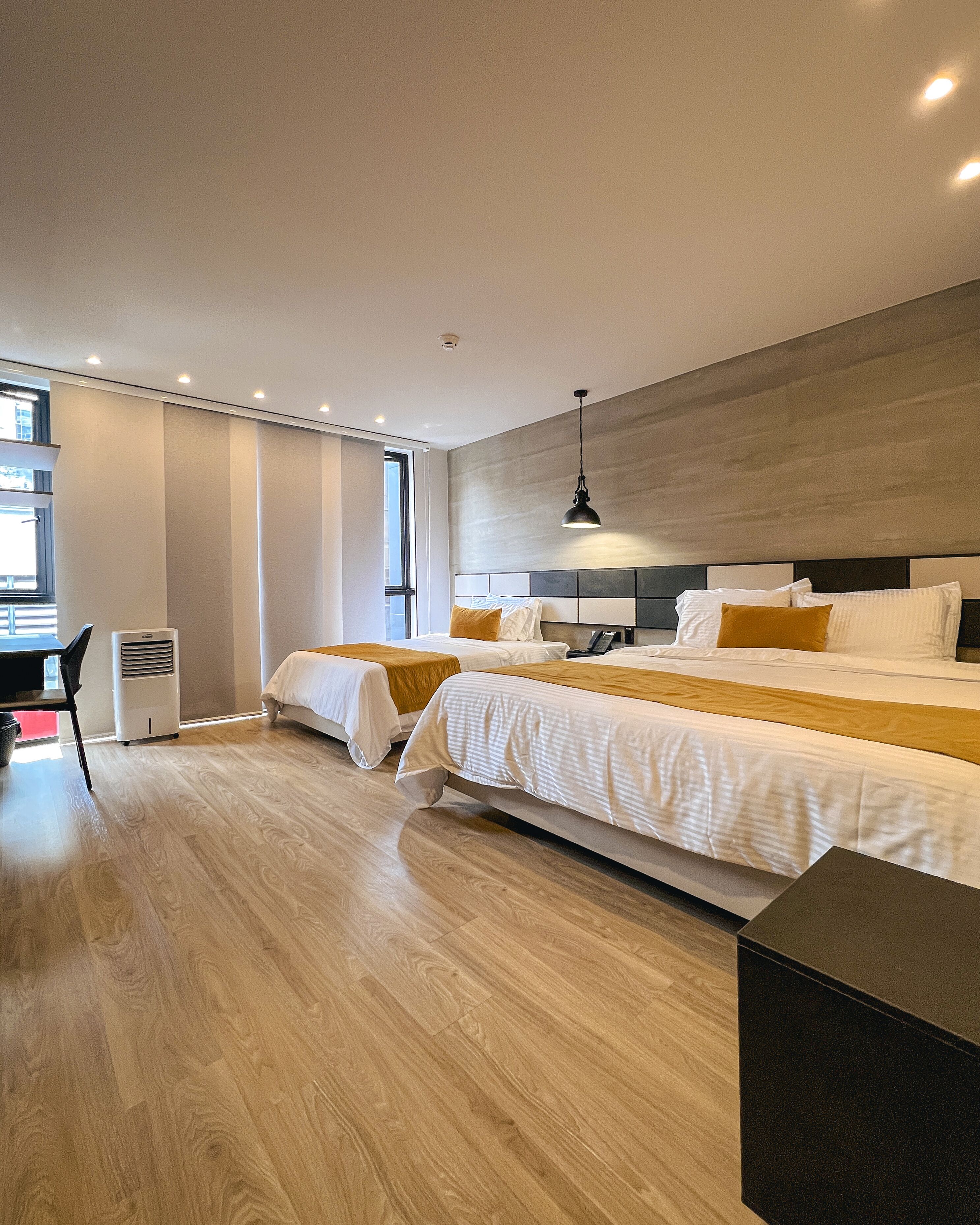 Une chambre d’hôtel moderne avec deux lits, un bureau et une grande fenêtre.