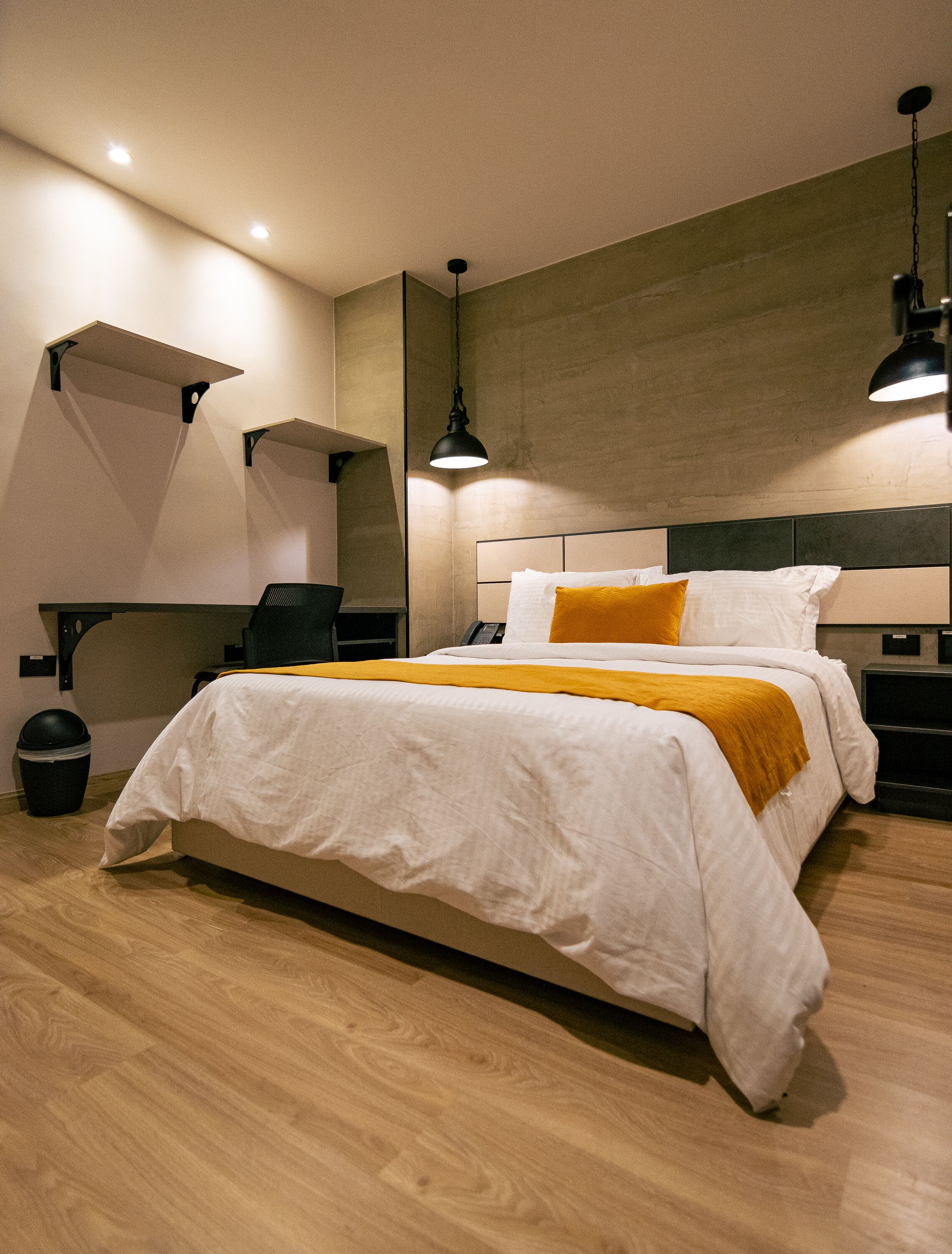 A modern hotel room with a large bed, a desk, and a chair.