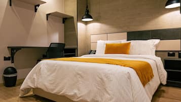 A modern hotel room with a large bed, a desk, and a chair.