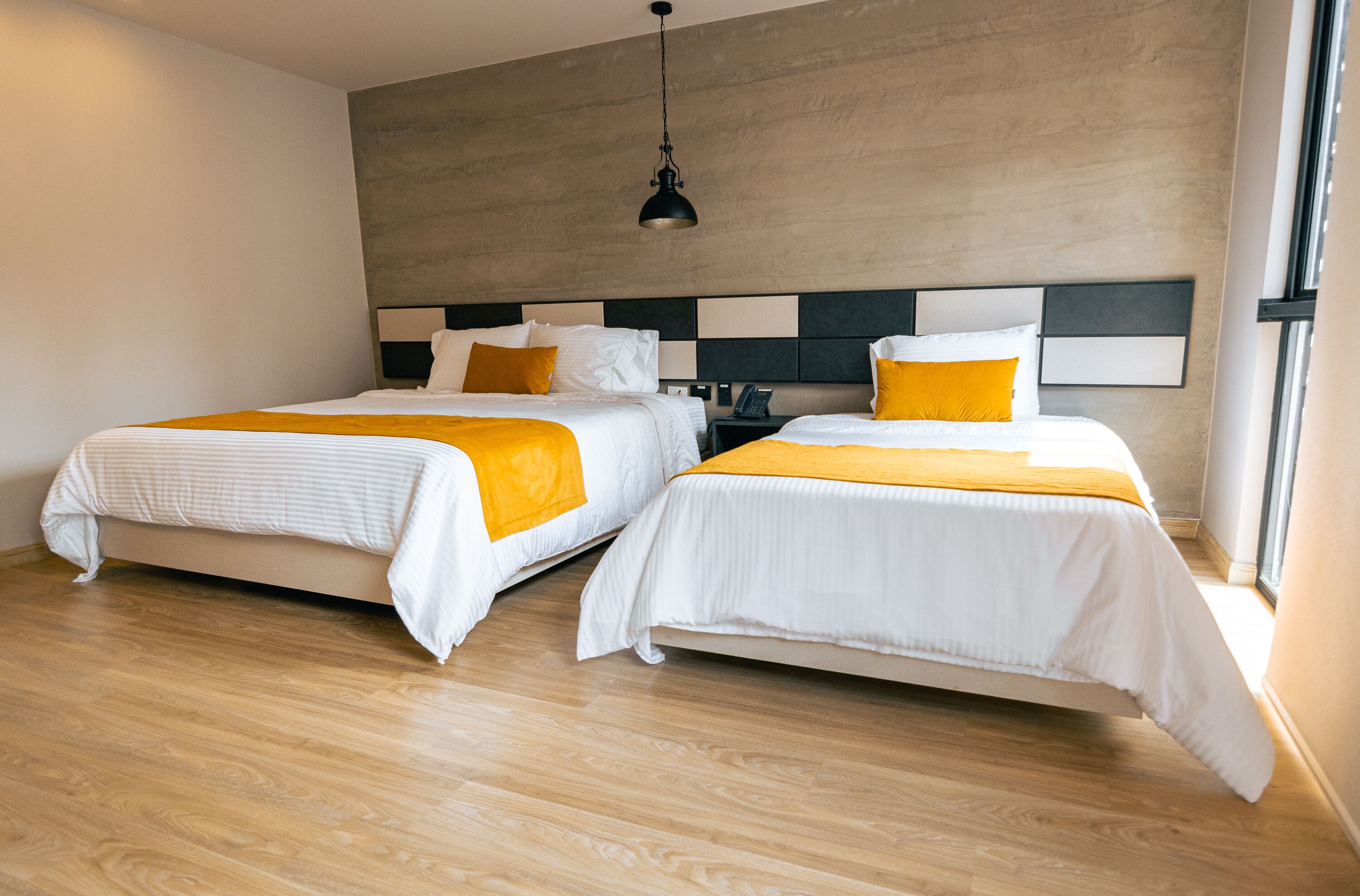 Una habitación de hotel moderna con dos camas, suelo de madera y un gran ventanal.