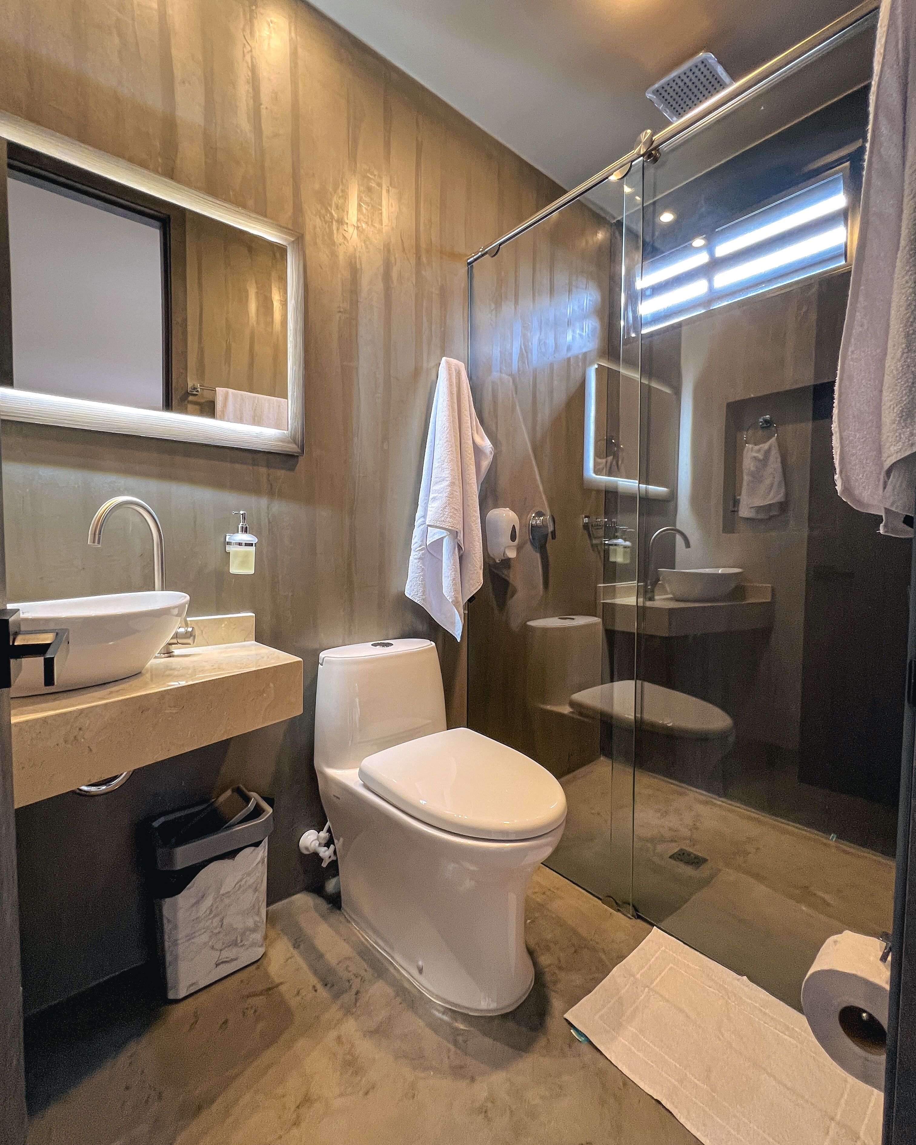 A modern bathroom with a glass-enclosed shower, a white toilet, a sink, and a mirror above the vanity.