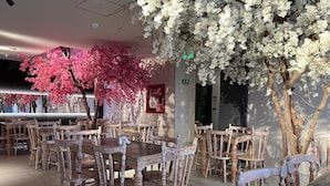 A restaurant with wooden tables and chairs, a ceiling with recessed lighting, and artificial cherry blossom trees. - Hotel Balmoral Plaza (Pereira)