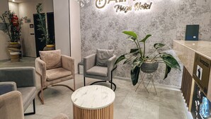 A modern hotel lobby with a chandelier, plush seating, and a marble wall with the hotel name. - Hotel Balmoral Plaza (Pereira)