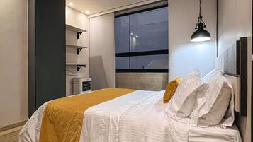 A modern bedroom with a bed, a window, and a hanging light fixture.