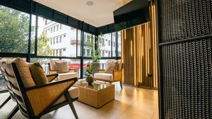 A modern interior with large windows, wicker furniture, and a view of buildings outside. - Hotel Balmoral Plaza (Pereira)