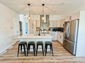 Una cocina moderna con una isla central, electrodomésticos de acero inoxidable y un suelo de madera con diseño espiga.