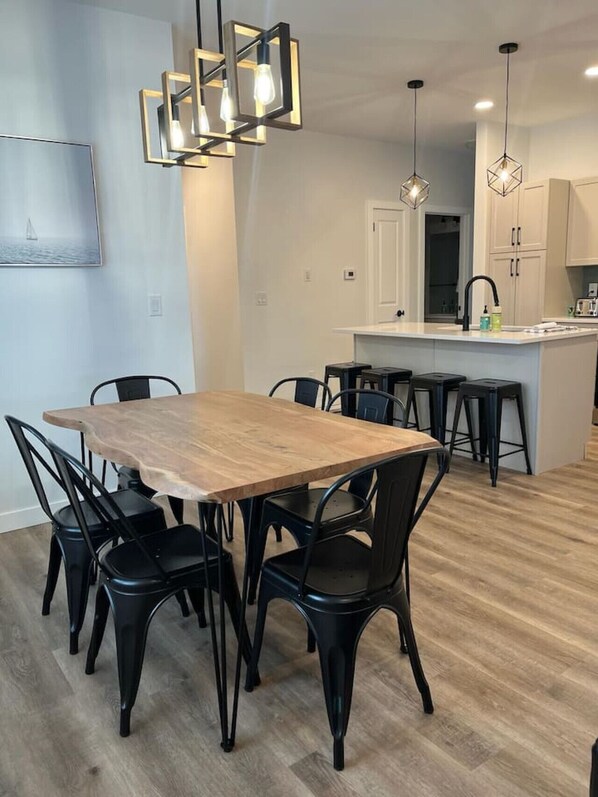 Cocina moderna con una isla central, sillas negras e iluminación colgante.