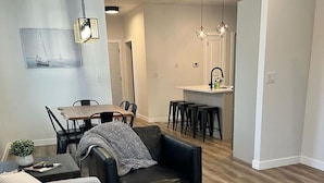 A modern living room with a sofa, a coffee table, and a dining area with a table and chairs.