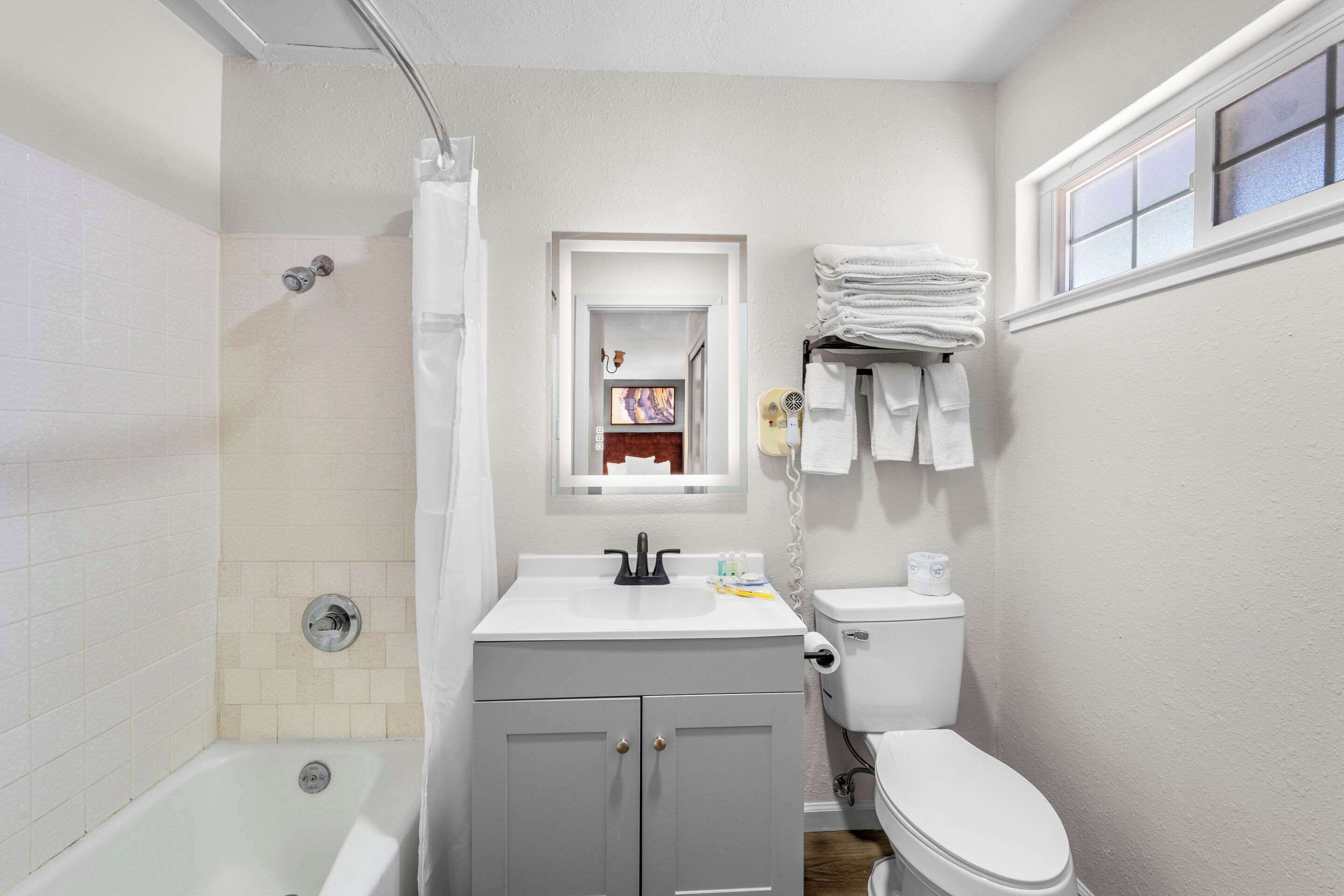 A bathroom with a bathtub, toilet, sink, and a window.