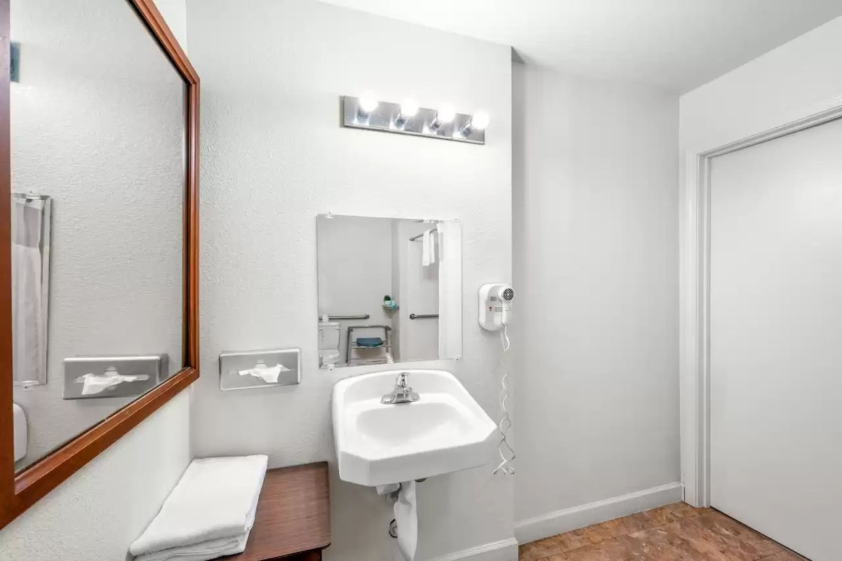 A bathroom with a white sink, a mirror, a towel rack, and a hairdryer.