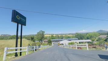 A road leading to a property with a sign for 'Quality Inn & Suites by CHICAGO HOTEL'.