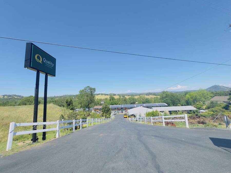 A road leading to a property with a sign for 'Quality Inn & Suites by CHICAGO HOTEL'.