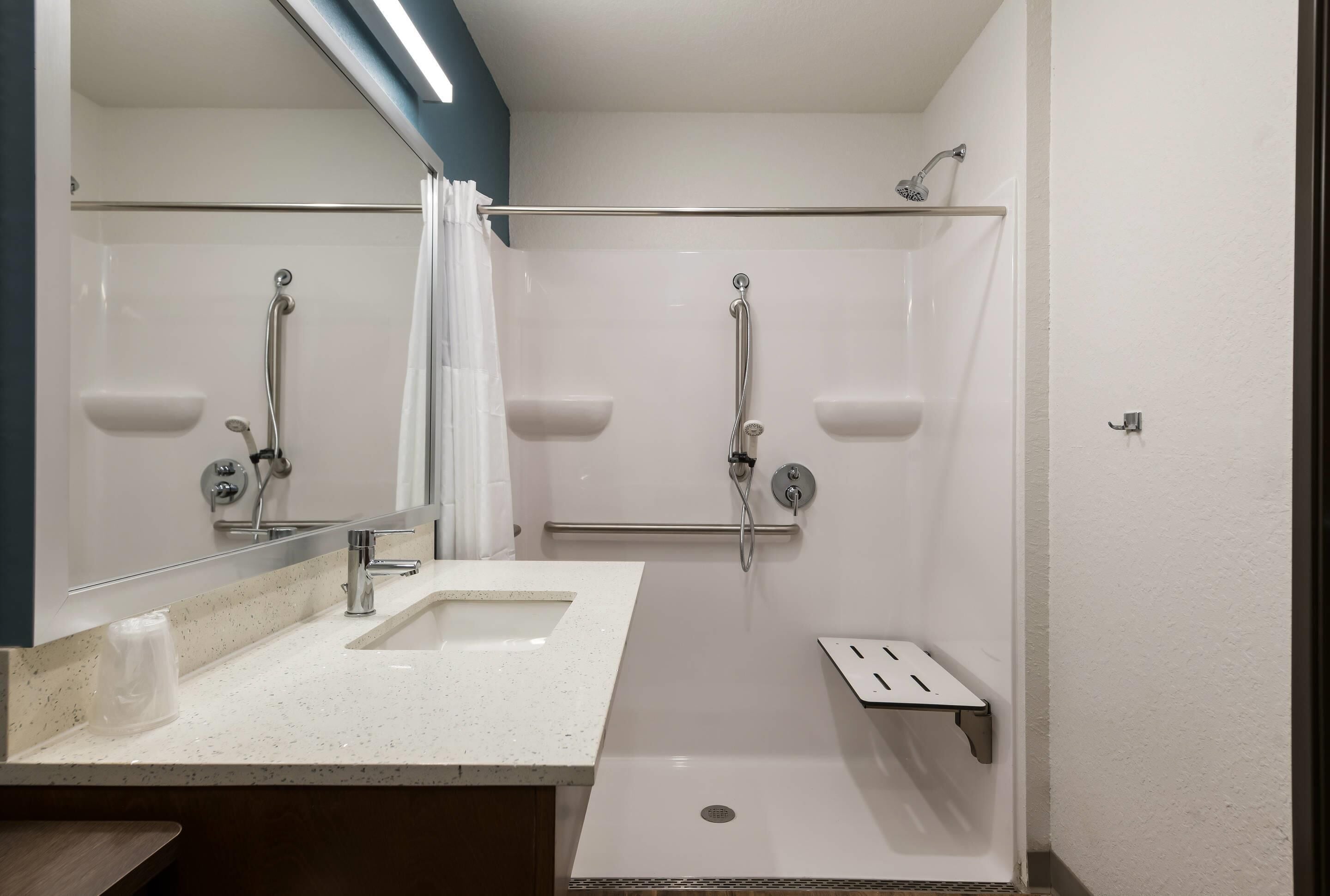 A modern bathroom with two sinks, a shower area, and a mirror.