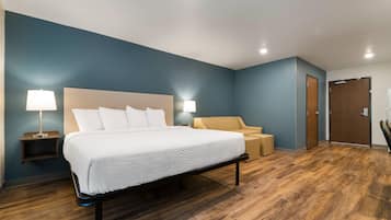 A hotel room with a bed, bedside lamps, a nightstand, a chair, and a wooden floor.