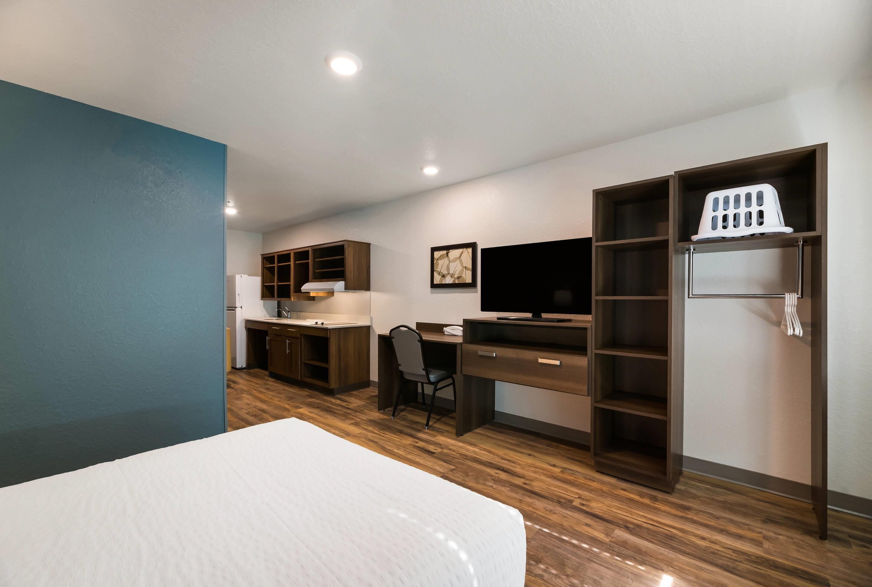 Una habitació d'hotel amb un llit, una taula de nit, una cadira, un televisor i un armari.