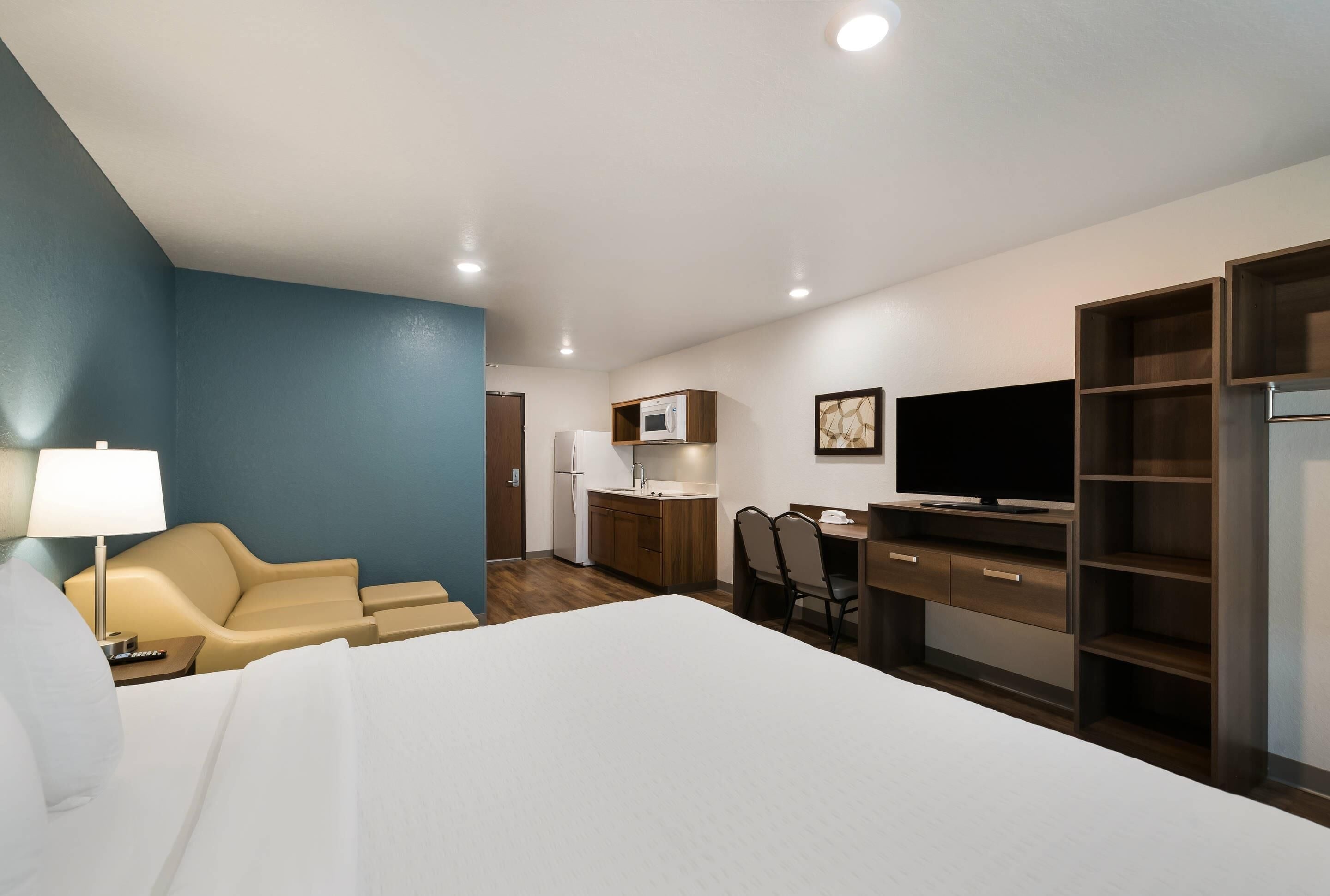 A hotel room with a bed, a desk, a TV, a microwave, and a seating area.