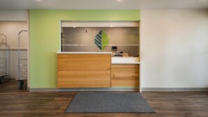 A modern office space with a wooden desk, a green accent wall, and a leaf-shaped decoration. - WoodSpring Suites Cocoa Beach - Rockledge (Rockledge)