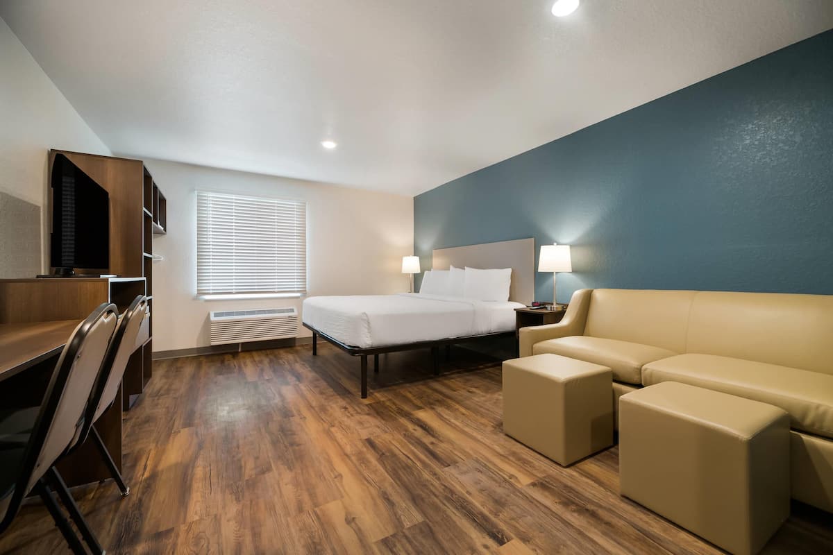 A hotel room with a bed, a sofa, a desk, and a TV.