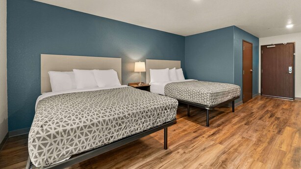 Ein Hotelzimmer mit zwei Betten, Holzboden und einer blauen Akzentwand.
