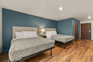 Una habitación de hotel con dos camas, suelo de madera y una pared azul decorativa.