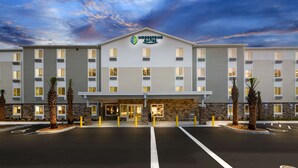 Ein Hotel mit moderner Fassade, mehreren Eingängen und einem Parkplatz.