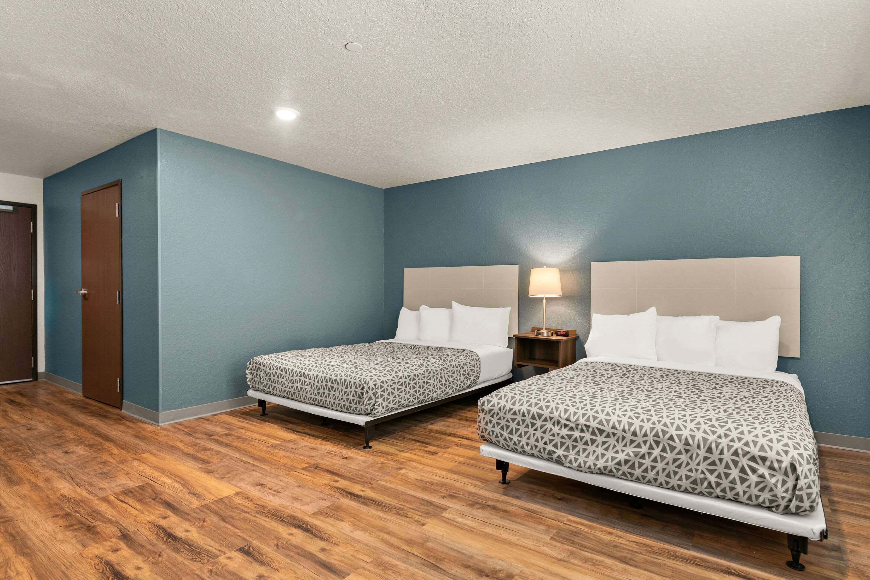 A hotel room with two beds, wooden flooring, and blue walls.