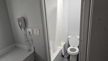 A bathroom with a shower, toilet, and a hairdryer on the wall.