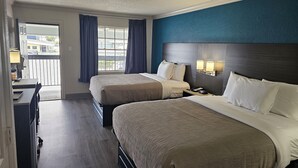 A hotel room with two beds, a desk with a lamp, and a view of the outside. - Quality Inn & Suites (Metairie)