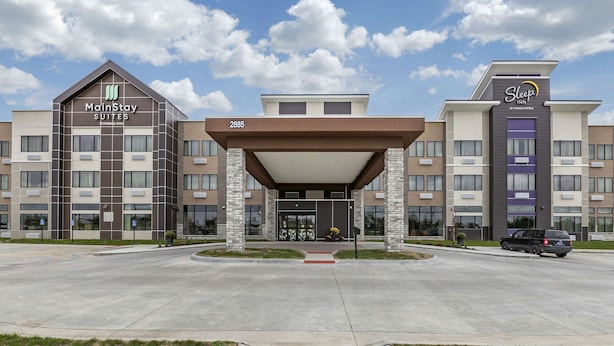 A hotel with MainStay Suites and Sleep Inn by Choice Hotels. It features a modern design with a covered entrance and a parking lot. - Sleep Inn & Suites Milwaukee/Franklin (Franklin)