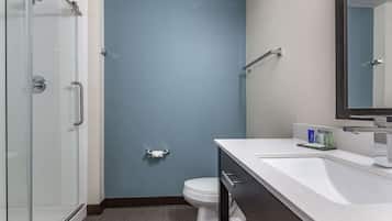 Une salle de bain moderne avec une douche à parois de verre, des toilettes blanches et un lavabo blanc avec un miroir au-dessus.