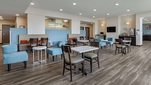 A modern hotel lobby with multiple seating areas, including sofas and tables, and a visible kitchen area in the background. - Sleep Inn & Suites Milwaukee/Franklin (Franklin)