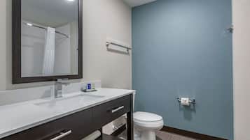 A bathroom with a white sink, dark-toned vanity, a mirror, a towel rack, and a toilet.
