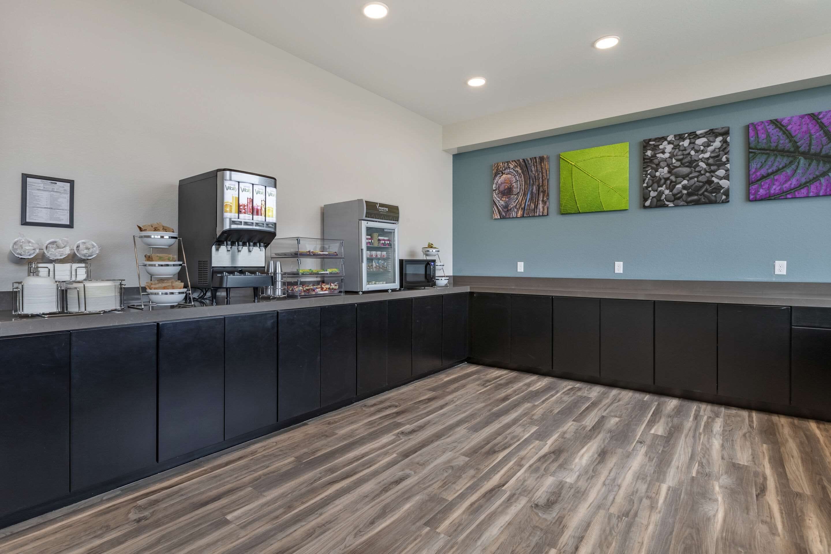 A modern reception area with a coffee machine, a refrigerator, and a counter with various items.
