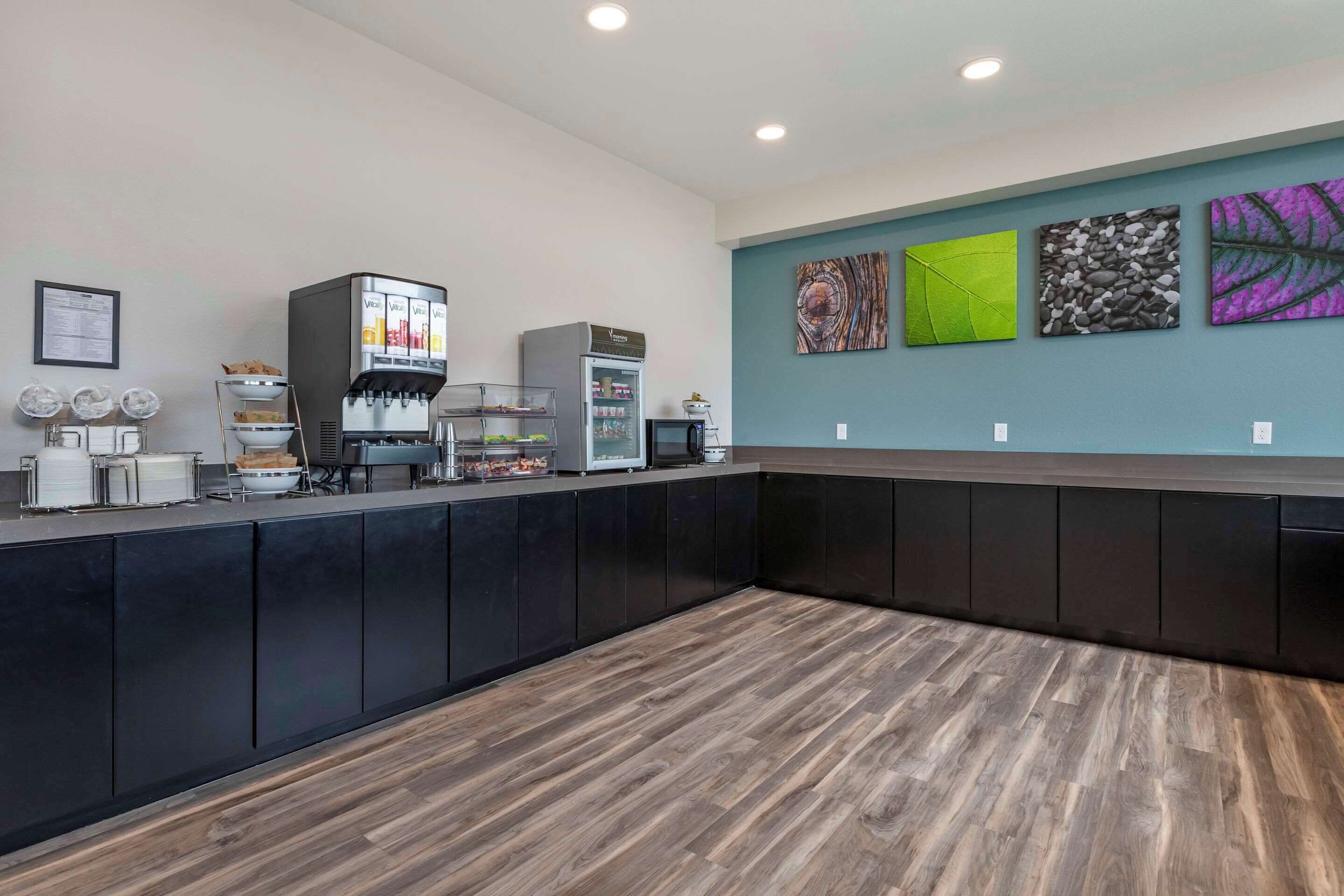 A modern reception area with a coffee machine, a refrigerator, and a counter with various items.
