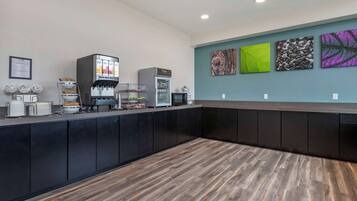 Una moderna zona de recepción con una cafetera, un refrigerador y un mostrador con diversos artículos.