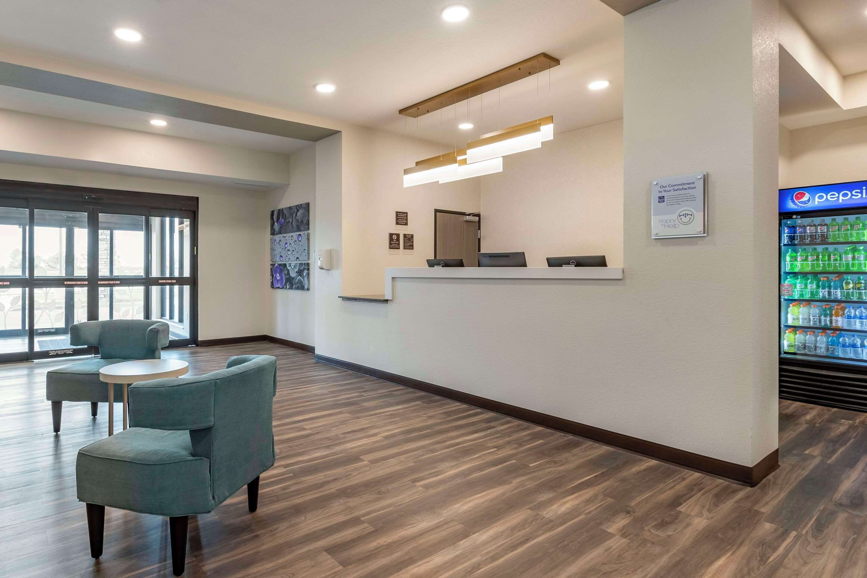 A reception area with a counter, seating, a refrigerator stocked with beverages, and a large window.