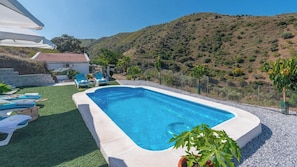 Una piscina rettangolare con bordo bianco, circondata da un'area ghiaiata e prato artificiale verde.