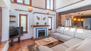 Un salón espacioso con chimenea, un sofá grande y un televisor.